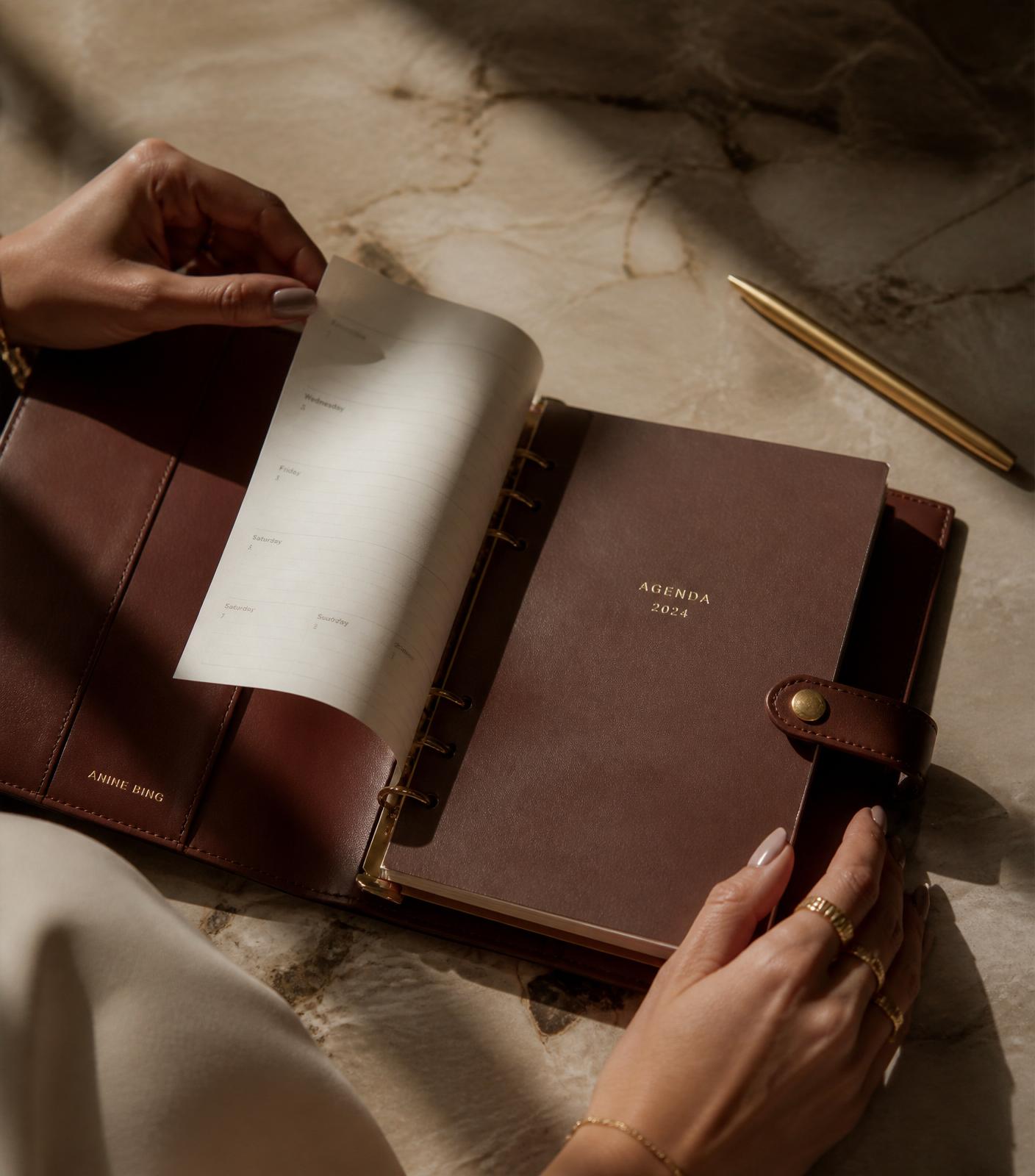 Detalhe close-up de agenda de couro com hot stamping dourado e caneta executiva